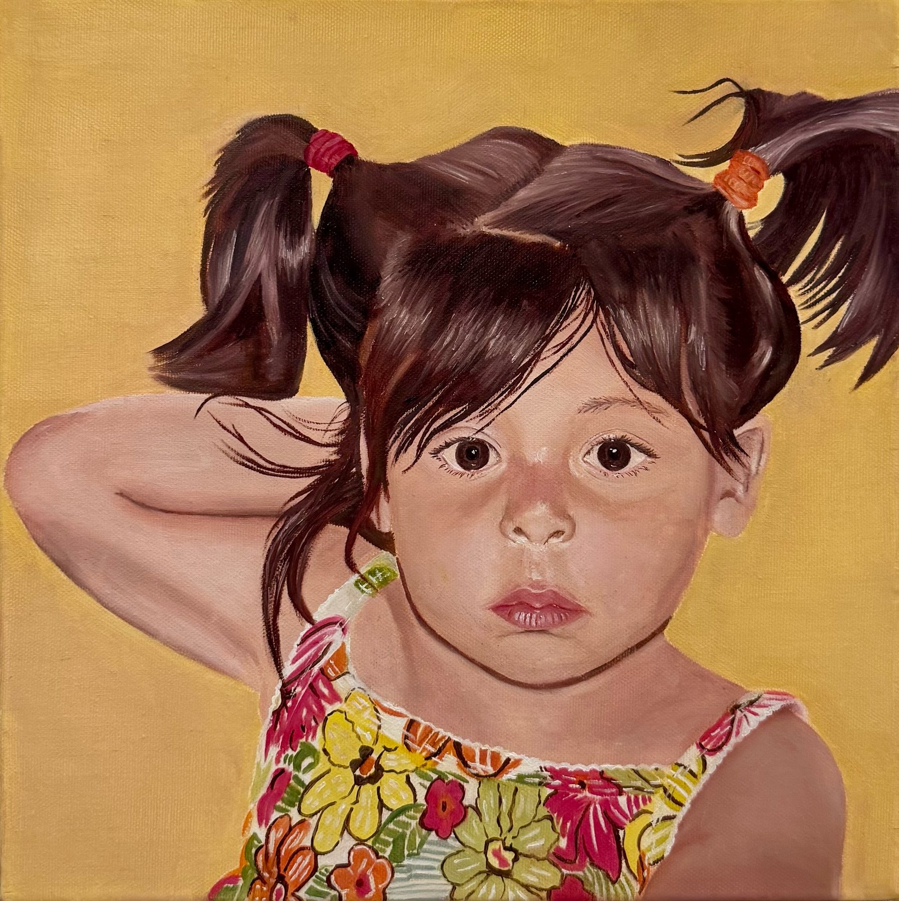 Portrait of a young girl with pigtails in a floral top, one arm raised behind her head, on a warm yellow background.